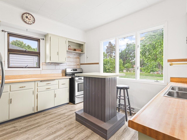 2242 S 5th St, Rockford, IL 61104 - kitchen with gas stove, light countertops, open shelves, light wood-style flooring, and decorative backsplash