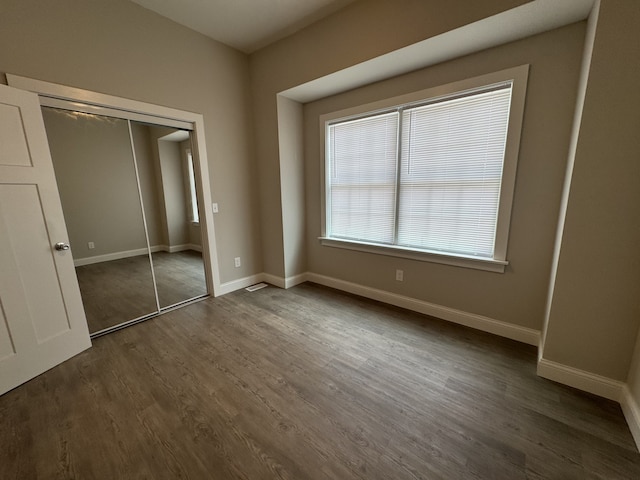 207 W Graham St, Bloomington, IL 61701 - unfurnished bedroom with dark wood-style flooring and a closet