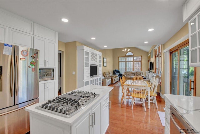 1505 Della Dr, Hoffman Estates, IL 60169 - kitchen with stainless steel appliances, light wood finished floors, white cabinetry, vaulted ceiling, and a kitchen island
