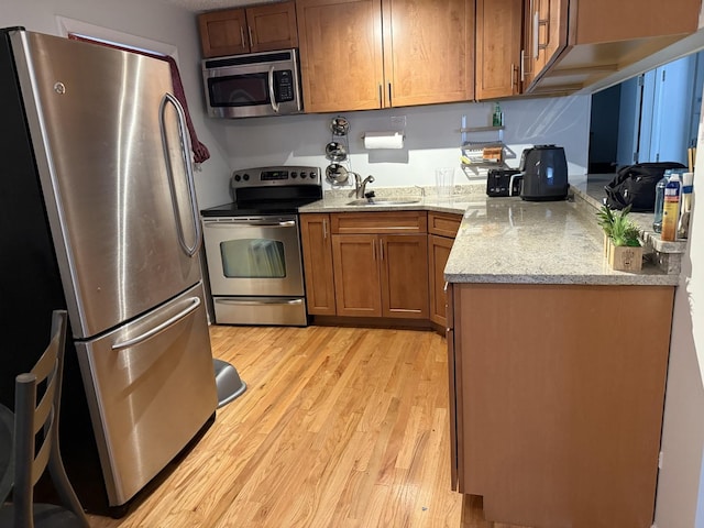 9513 Kelvin Ln Unit 2111, Schiller Park, IL 60176 - kitchen featuring appliances with stainless steel finishes, light wood-style floors, brown cabinets, and light stone counters