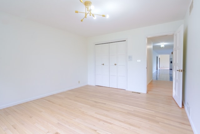 921 Cassie Dr, Joliet, IL 60435 - unfurnished bedroom featuring a chandelier, light wood-style flooring, and a closet