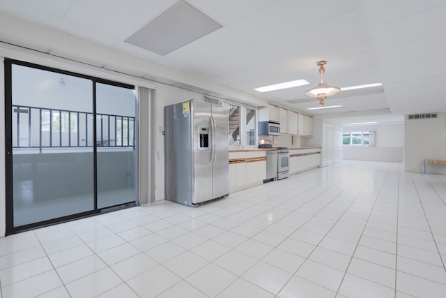 921 Cassie Dr, Joliet, IL 60435 - kitchen with stainless steel appliances, light countertops, light tile patterned floors, white cabinets, and pendant lighting