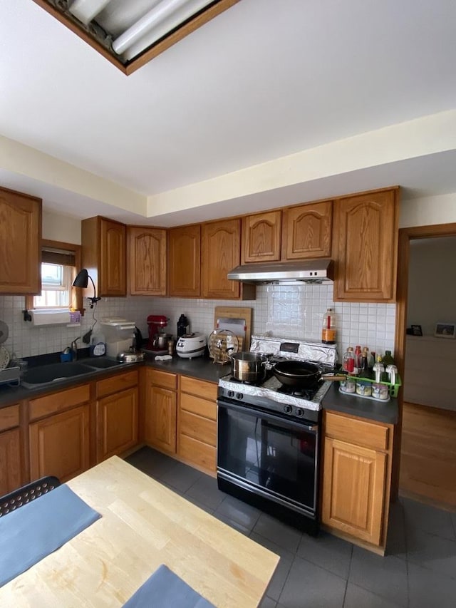 461 W 28th Pl, Chicago, IL 60616 - kitchen featuring black gas range, under cabinet range hood, backsplash, and brown cabinetry