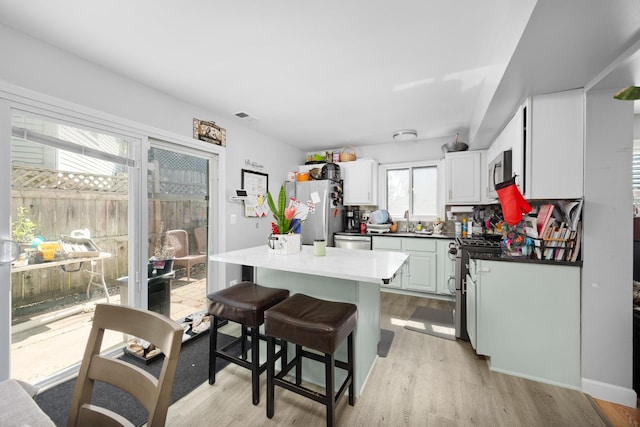 1100 Singleton Dr, Roselle, IL 60172 - kitchen featuring stainless steel appliances, a center island, light wood-style floors, a breakfast bar, and white cabinets