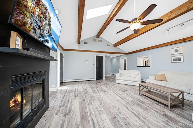 5821 W 127th St, Palos Heights, IL 60463 - living area with a baseboard heating unit, a ceiling fan, a glass covered fireplace, wood finished floors, and a skylight