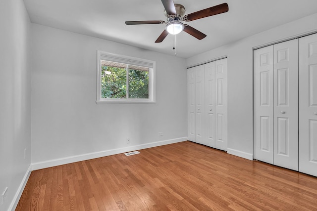 1549 Revere Cir, Schaumburg, IL 60193 - unfurnished bedroom featuring two closets, light wood-style flooring, and ceiling fan