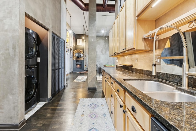 1215 W Gunnison St Unit 202, Chicago, IL 60640 - kitchen with stacked washing machine and dryer, dark wood finished floors, light brown cabinets, dark stone counters, and dishwasher