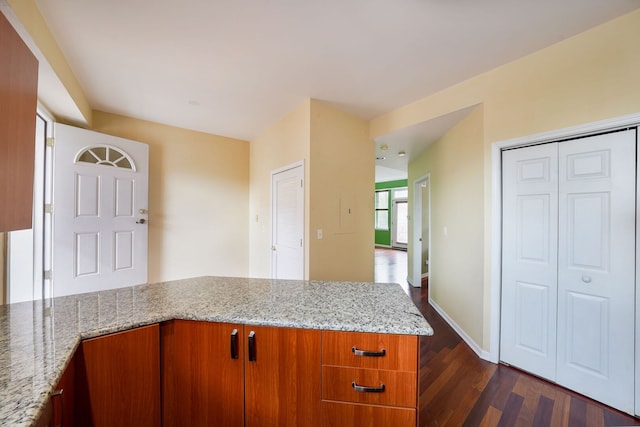 3002 W Montrose Ave Unit 2A, Chicago, IL 60618 - kitchen with a peninsula, dark wood-style floors, light stone countertops, and brown cabinetry