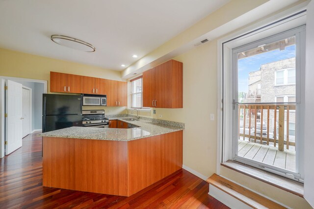 3002 W Montrose Ave Unit 2A, Chicago, IL 60618 - kitchen featuring stainless steel appliances, a peninsula, dark wood-style flooring, light stone counters, and brown cabinetry