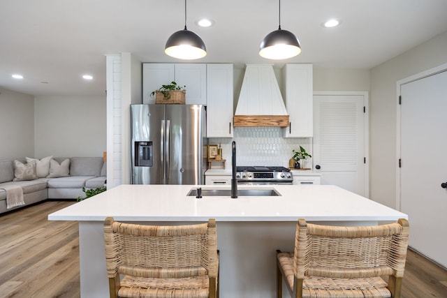 750 Shady Ln, Aurora, IL 60506 - kitchen with stainless steel appliances, custom exhaust hood, light wood finished floors, backsplash, and pendant lighting