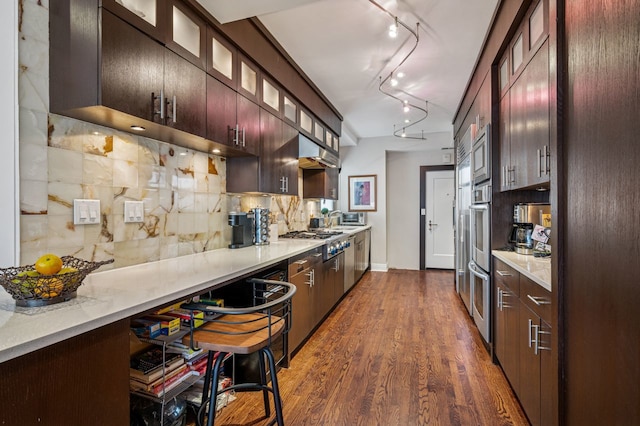 5000 S E End Ave Unit 18C, Chicago, IL 60615 - kitchen featuring stainless steel appliances, decorative backsplash, dark wood-type flooring, glass insert cabinets, and under cabinet range hood