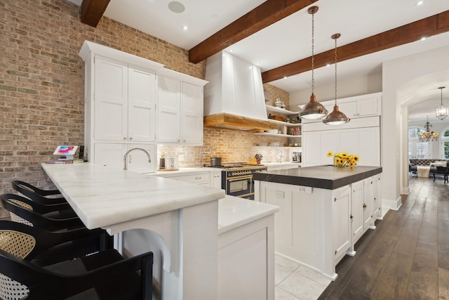 1414 N Mohawk St, Chicago, IL 60610 - kitchen with range with two ovens, custom exhaust hood, backsplash, a peninsula, and beamed ceiling
