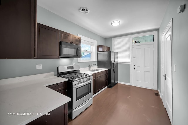 11402 S Calumet Ave, Chicago, IL 60628 - kitchen featuring black microwave, stainless steel range with gas stovetop, dark brown cabinetry, freestanding refrigerator, and light countertops