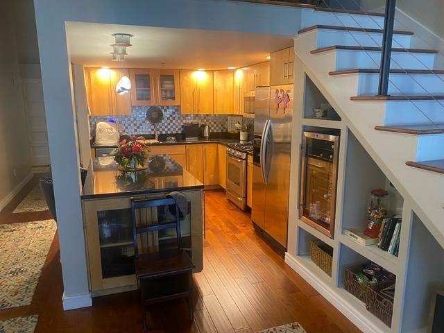 212 N Center St Unit 205, Bloomington, IL 61701 - kitchen featuring appliances with stainless steel finishes, dark wood-style floors, backsplash, glass insert cabinets, and decorative light fixtures