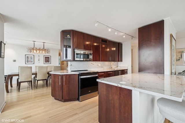 1560 N Sandburg Ter Unit 4301-4303, Chicago, IL 60610 - kitchen featuring appliances with stainless steel finishes, light wood-type flooring, glass insert cabinets, a peninsula, and decorative backsplash