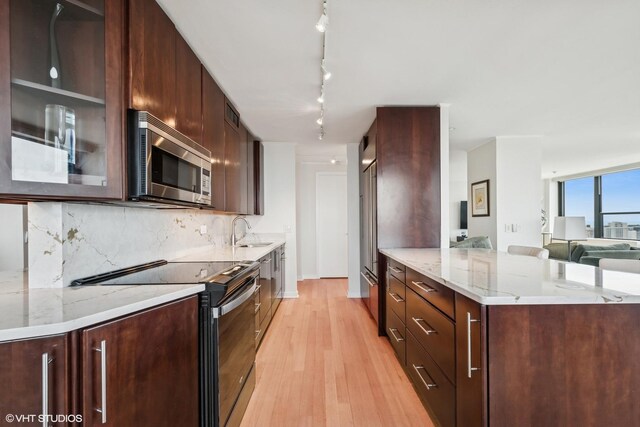 1560 N Sandburg Ter Unit 4301-4303, Chicago, IL 60610 - kitchen featuring stainless steel microwave, range with electric stovetop, a peninsula, light wood-style floors, and track lighting