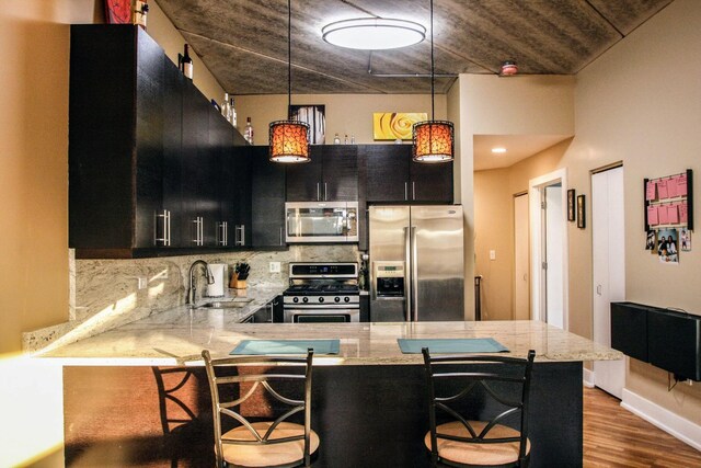 3201 W Leland Ave Unit 406, Chicago, IL 60625 - kitchen with stainless steel appliances, dark cabinetry, backsplash, wood finished floors, and decorative light fixtures