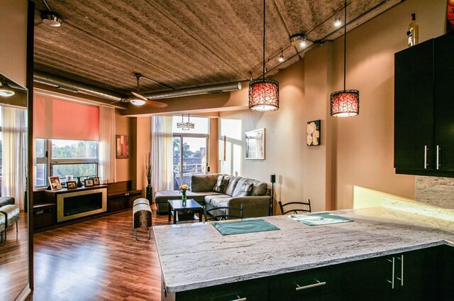 3201 W Leland Ave Unit 406, Chicago, IL 60625 - kitchen featuring wood finished floors, hanging light fixtures, a peninsula, dark cabinetry, and light stone counters