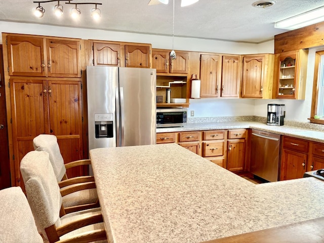 1217 Retz Dr, Ottawa, IL 61350 - kitchen with stainless steel appliances, light countertops, brown cabinets, a kitchen bar, and glass insert cabinets