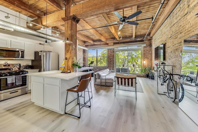 1740 N Maplewood Ave Unit 301, Chicago, IL 60647 - kitchen with appliances with stainless steel finishes, a wood ceiling with exposed beams, light wood-style flooring, brick wall, and open floor plan