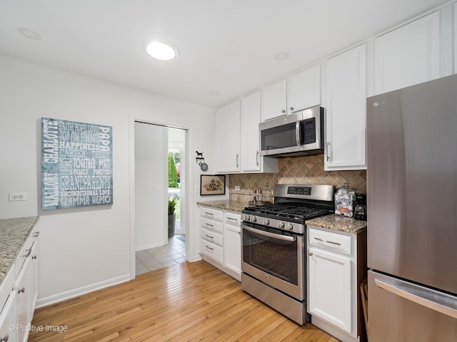 711 Bryant Ave, Barrington, IL 60010 - kitchen featuring appliances with stainless steel finishes, tasteful backsplash, white cabinets, light stone counters, and light wood-style floors