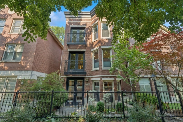 1725 N Fremont St, Chicago, IL 60614 - back of house with brick siding, a fenced front yard, a balcony, and french doors