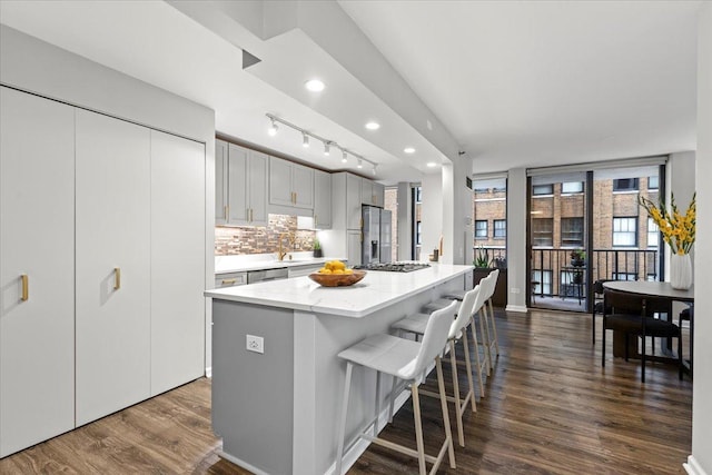1230 N State Pkwy Unit 7D, Chicago, IL 60610 - kitchen featuring stainless steel refrigerator with ice dispenser, dark wood-type flooring, backsplash, light stone countertops, and a kitchen island