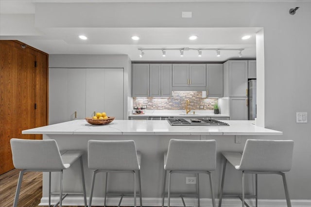 1230 N State Pkwy Unit 7D, Chicago, IL 60610 - kitchen with stainless steel gas cooktop, backsplash, wood finished floors, fridge, and a breakfast bar