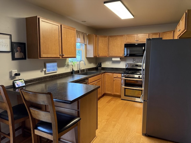 6 Kimberly Dr, Spring Valley, IL 61362 - kitchen featuring stainless steel appliances, a peninsula, a breakfast bar, light wood-style flooring, and dark countertops