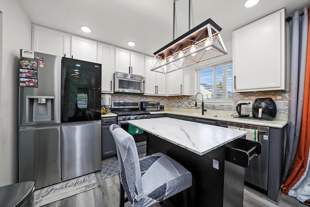 1024 Birchwood Dr, Pingree Grove, IL 60140 - kitchen featuring stainless steel appliances, light wood finished floors, a breakfast bar area, white cabinets, and backsplash