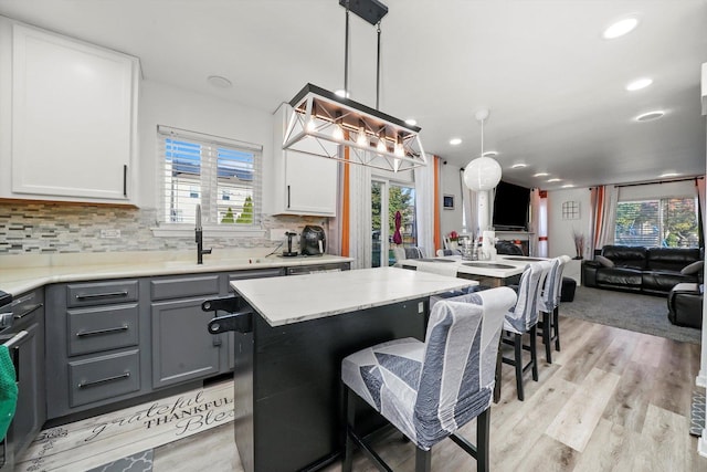 1024 Birchwood Dr, Pingree Grove, IL 60140 - kitchen featuring open floor plan, gray cabinets, light wood finished floors, a kitchen bar, and backsplash