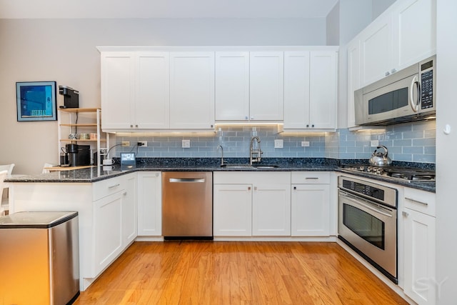 909 W Village Ct, Chicago, IL 60608 - kitchen featuring appliances with stainless steel finishes, white cabinets, light wood finished floors, backsplash, and a peninsula