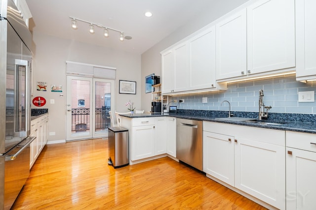909 W Village Ct, Chicago, IL 60608 - kitchen featuring appliances with stainless steel finishes, a peninsula, light wood-style flooring, tasteful backsplash, and white cabinetry
