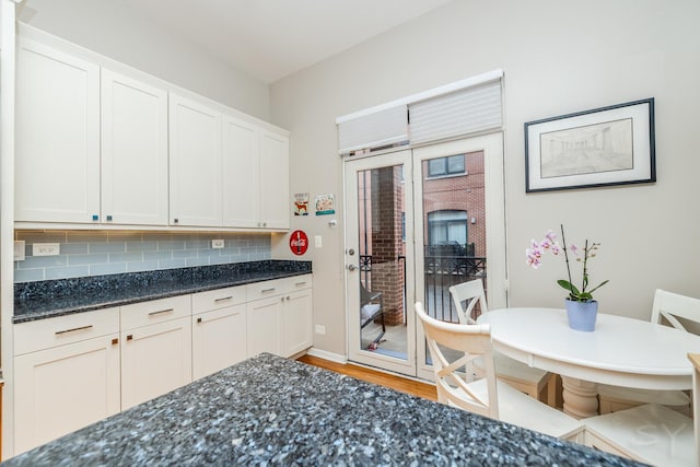 909 W Village Ct, Chicago, IL 60608 - kitchen with light wood-type flooring, dark stone counters, decorative backsplash, and white cabinetry