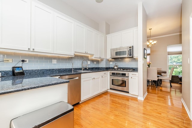 909 W Village Ct, Chicago, IL 60608 - kitchen with appliances with stainless steel finishes, light wood finished floors, decorative backsplash, white cabinets, and crown molding