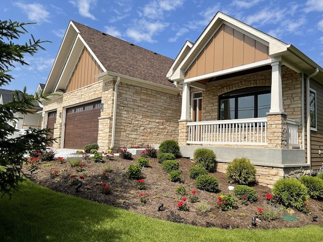 7625 Dunham Rd, Woodridge, IL 60517 - craftsman inspired home featuring stone siding, a porch, board and batten siding, a garage, and a shingled roof