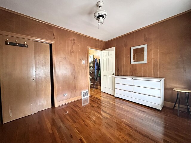 4440 W Iowa St, Chicago, IL 60651 - unfurnished bedroom featuring wood finished floors, wood walls, and a closet