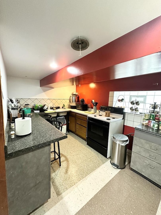 4440 W Iowa St, Chicago, IL 60651 - kitchen featuring white range with electric cooktop, tasteful backsplash, dark countertops, and light flooring