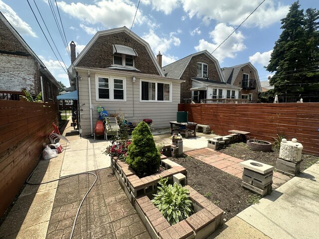 4440 W Iowa St, Chicago, IL 60651 - rear view of house with a patio, a gambrel roof, and a chimney