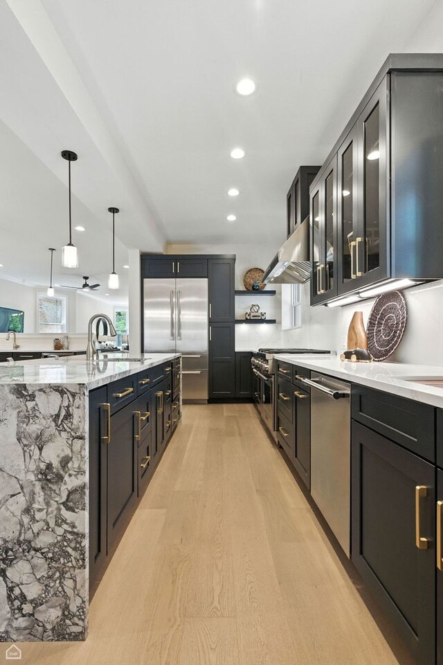 4525 N Artesian Ave, Chicago, IL 60625 - kitchen with high end appliances, ventilation hood, light wood-style floors, light stone countertops, and decorative light fixtures