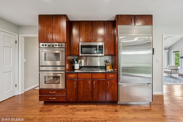10 N Highview Cir, Hawthorn Woods, IL 60047 - kitchen with stainless steel appliances, wood finished floors, backsplash, and dark countertops