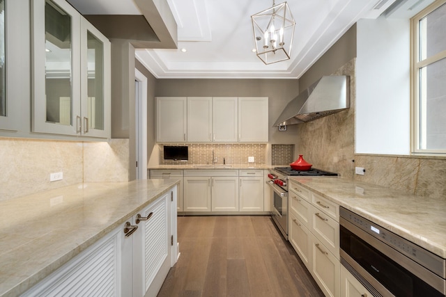 118 E Erie St Unit 21C, Chicago, IL 60611 - kitchen with wall chimney range hood, appliances with stainless steel finishes, dark wood-type flooring, white cabinets, and tasteful backsplash