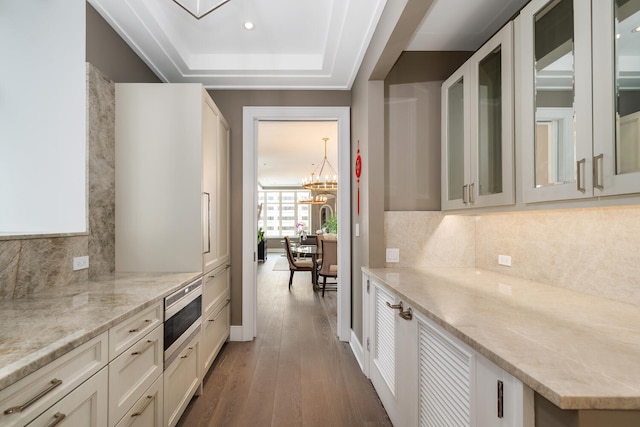 118 E Erie St Unit 21C, Chicago, IL 60611 - kitchen with stainless steel microwave, wood finished floors, glass insert cabinets, light stone countertops, and decorative backsplash