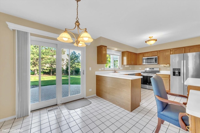 1175 Oxford Ct, Lake Zurich, IL 60047 - kitchen with appliances with stainless steel finishes, a peninsula, light countertops, pendant lighting, and a chandelier