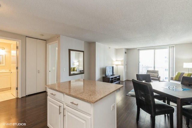 545 N Dearborn St Unit 2603, Chicago, IL 60654 - kitchen featuring open floor plan, a textured ceiling, dark wood-style flooring, a kitchen island, and white cabinets