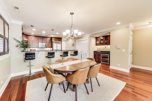 846 W Roscoe St Unit 3W, Chicago, IL 60657 - dining room with recessed lighting, beverage cooler, a chandelier, crown molding, and light wood-type flooring