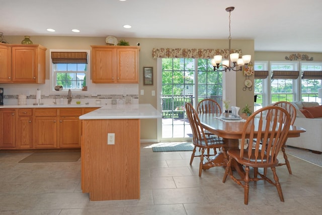 3115 Sable Oaks Rd, Bloomington, IL 61704 - kitchen featuring a chandelier, light countertops, tasteful backsplash, hanging light fixtures, and a peninsula