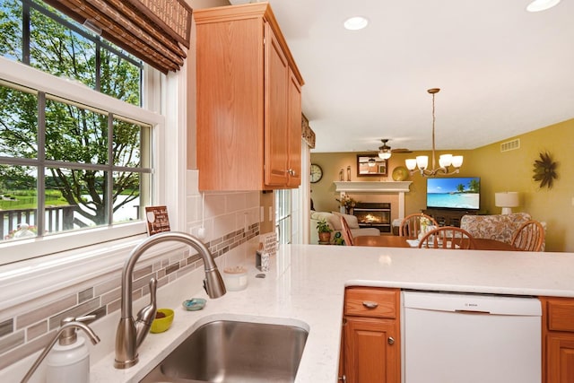 3115 Sable Oaks Rd, Bloomington, IL 61704 - kitchen with dishwasher, decorative backsplash, a lit fireplace, a ceiling fan, and pendant lighting
