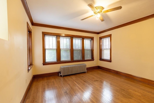 unfurnished room with radiator, light wood-type flooring, healthy amount of natural light, ornamental molding, and ceiling fan