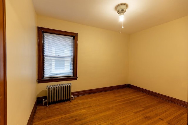 unfurnished room featuring radiator and wood finished floors